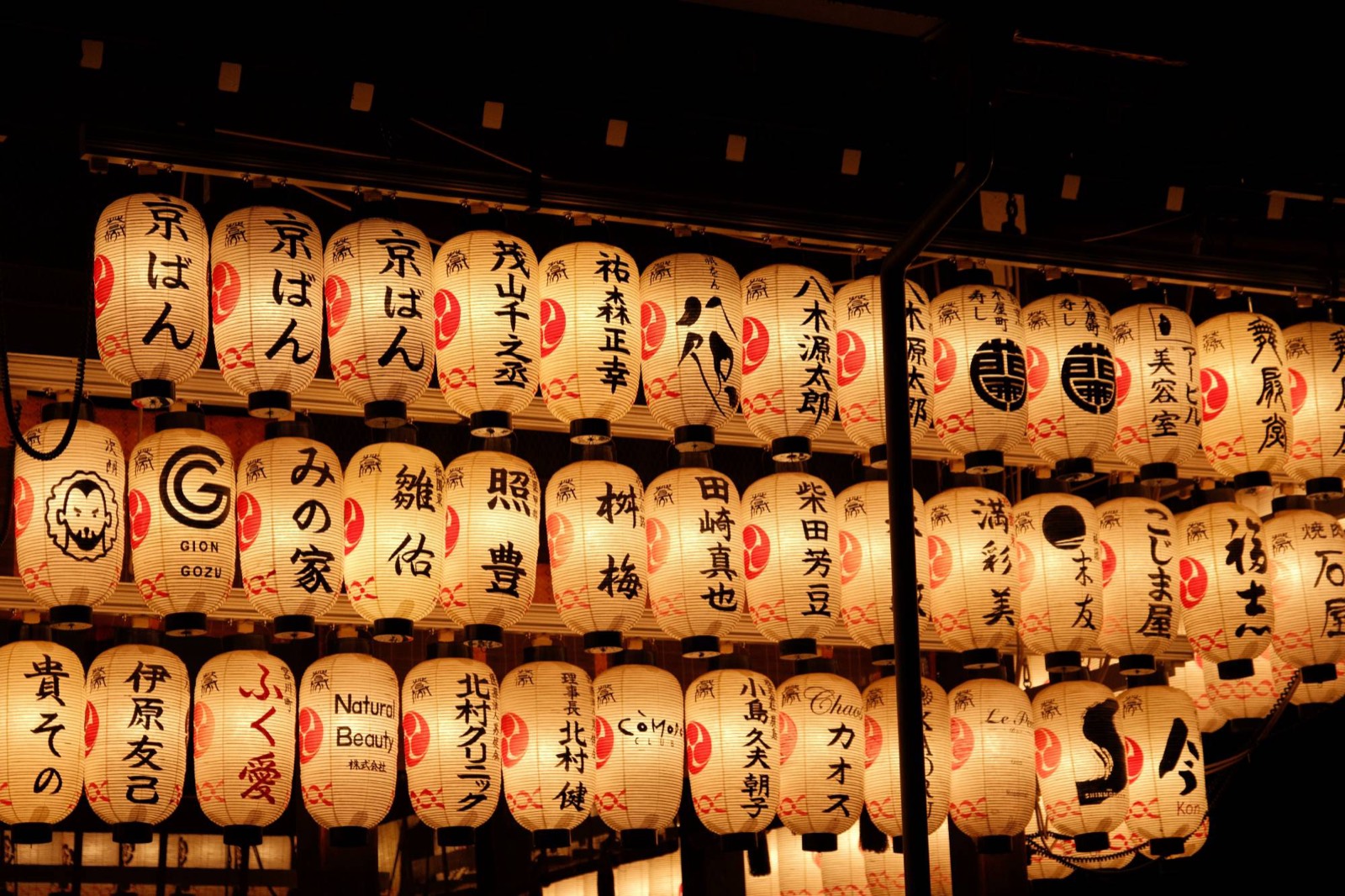 Close on rows of paper lanterns at Yasaka Shrine, glowing amber