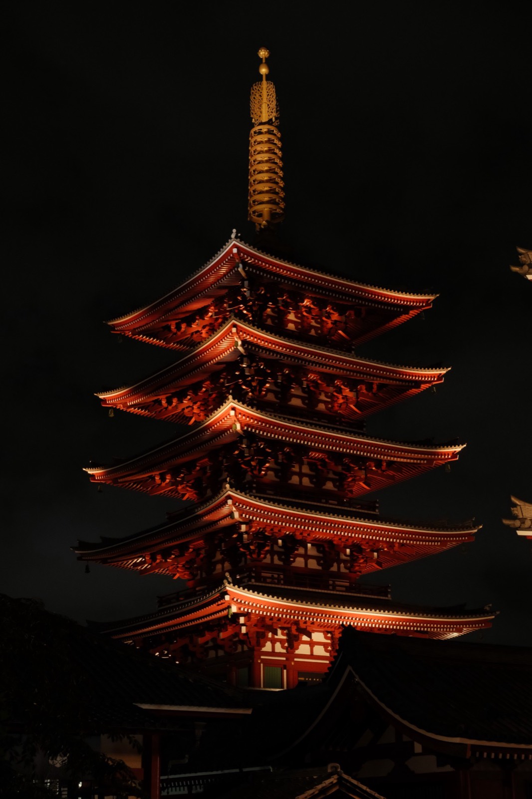 The five-storey pagoda at Senso-ji lit red at night against a black sky